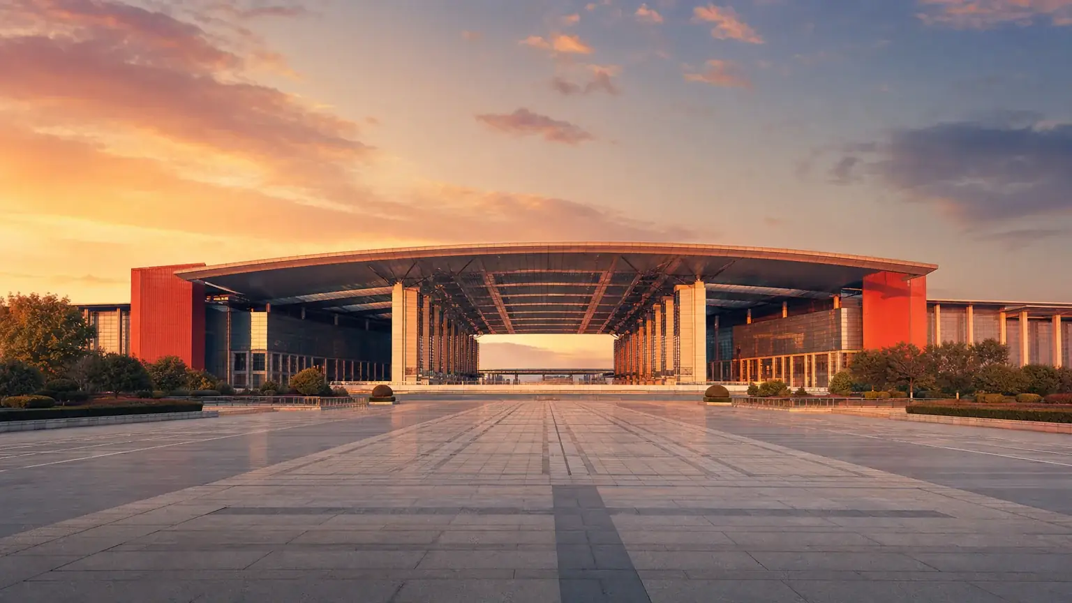 The entrance plaza of a Yiwu trade-city hall at sunrise, its long curved roof and empty forecourt before the buyers arrive